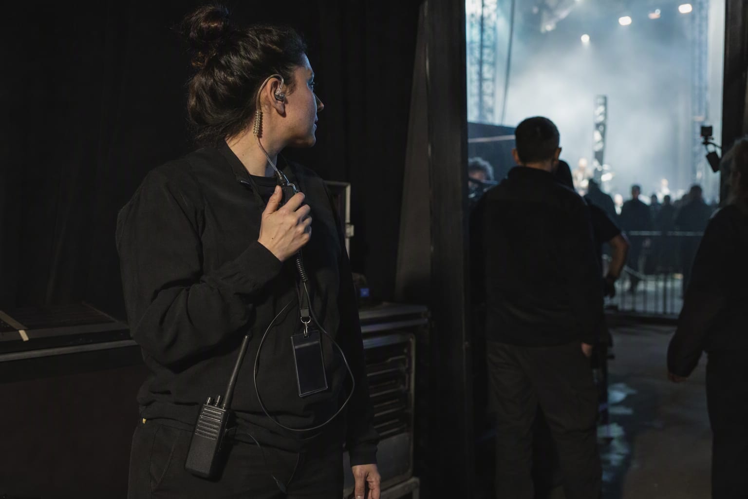 Equipo de producción coordina el backstage de un evento nocturno con público al fondo.